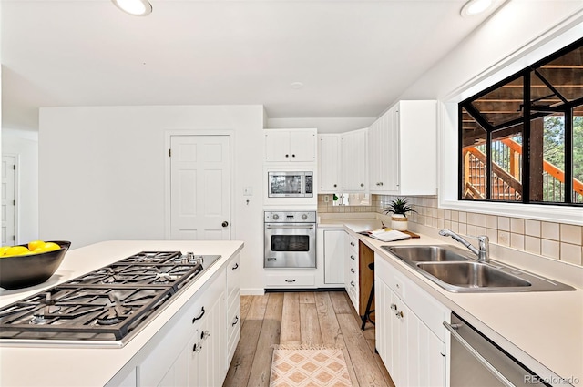 133 Mine Ln, Boulder, CO 80302 - kitchen featuring stainless steel appliances, light wood finished floors, light countertops, white cabinets, and decorative backsplash