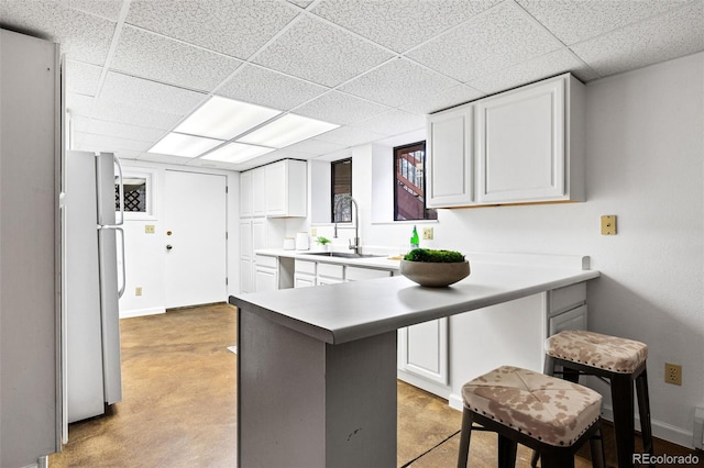 133 Mine Ln, Boulder, CO 80302 - kitchen featuring freestanding refrigerator, white cabinets, a paneled ceiling, concrete floors, and light countertops