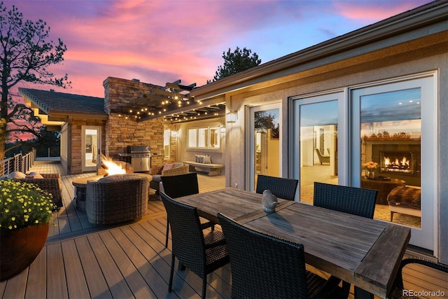 deck at dusk featuring a fire pit and grilling area