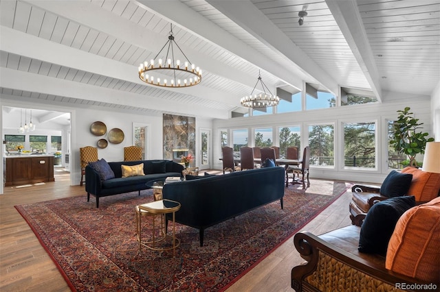 living room featuring vaulted ceiling with beams, a notable chandelier, and light hardwood / wood-style floors