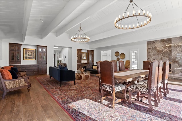 dining area with a notable chandelier, wood-type flooring, and vaulted ceiling with beams