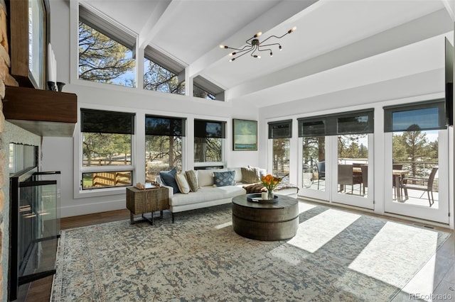 sunroom featuring vaulted ceiling with beams, a fireplace, a chandelier, and a healthy amount of sunlight