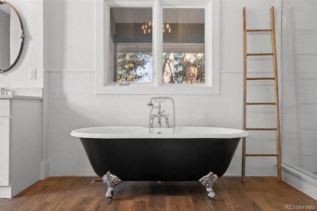 bathroom featuring vanity, hardwood / wood-style floors, tile walls, and a tub