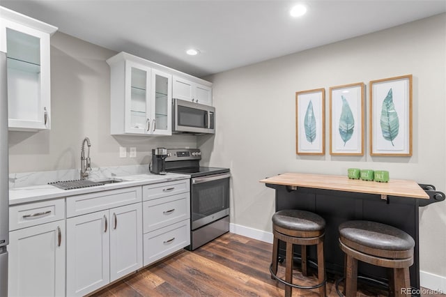 kitchen featuring a breakfast bar, wood counters, sink, white cabinets, and stainless steel appliances