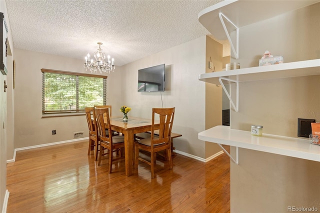 2876 S Wolff St, Denver, CO 80236 - dining space featuring light wood-style floors, a chandelier, and a textured ceiling