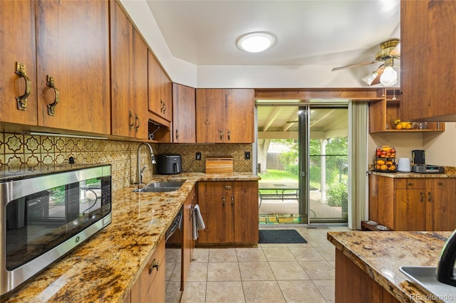 2876 S Wolff St, Denver, CO 80236 - kitchen with stainless steel microwave, dishwasher, backsplash, brown cabinets, and light tile patterned flooring