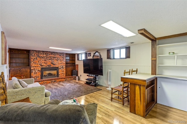 2876 S Wolff St, Denver, CO 80236 - living area with a textured ceiling, light wood-style floors, built in features, a brick fireplace, and wainscoting