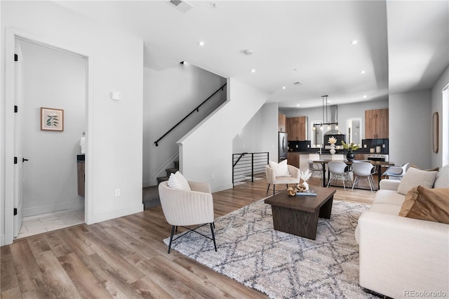 living area with recessed lighting, stairway, light wood-type flooring, and baseboards