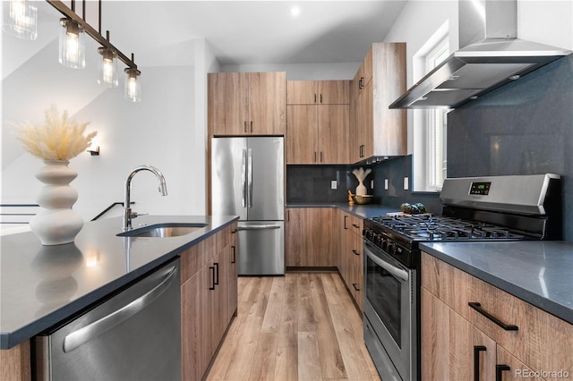 kitchen with stainless steel appliances, wall chimney range hood, a sink, light wood-type flooring, and decorative backsplash