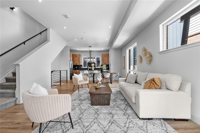 living room featuring recessed lighting, stairs, light wood-type flooring, and a chandelier