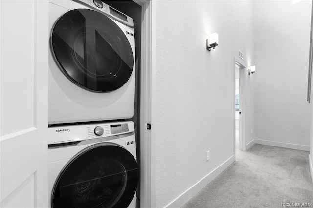 laundry room with stacked washing machine and dryer, light carpet, and baseboards