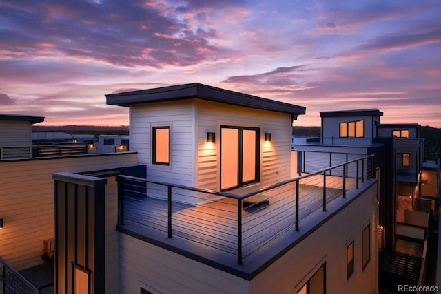 back of house at dusk featuring a balcony
