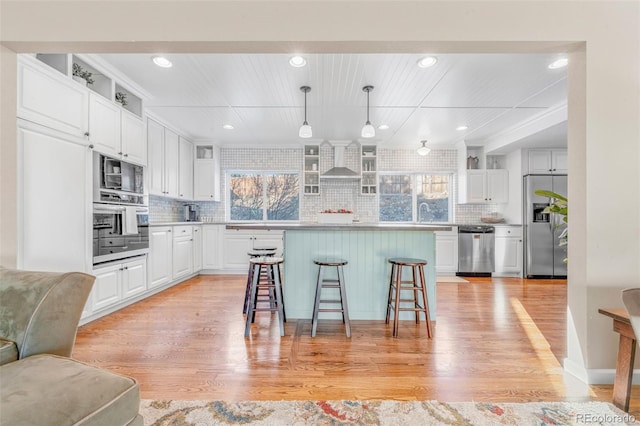 kitchen featuring a center island, a kitchen bar, white cabinets, decorative light fixtures, and stainless steel appliances