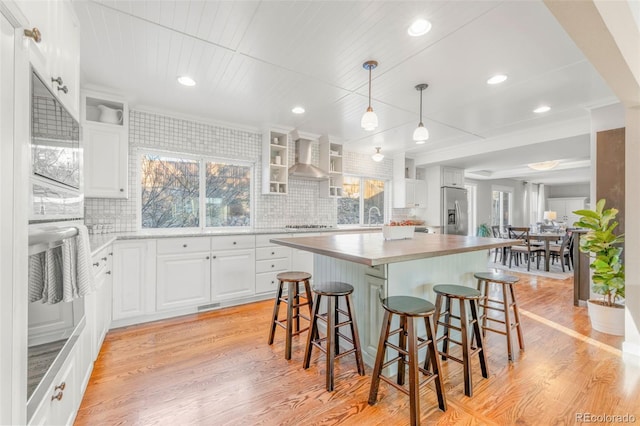 kitchen featuring light hardwood / wood-style flooring, pendant lighting, white cabinetry, a kitchen island, and decorative backsplash