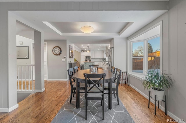 dining room with wood-type flooring and a raised ceiling