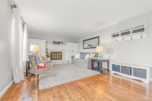 living room featuring a brick fireplace and light hardwood / wood-style flooring