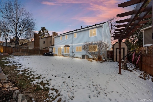 snow covered back of property featuring a storage unit