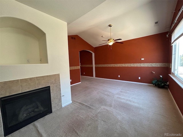 11207 Osage Cir Unit B, Northglenn, CO 80234 - unfurnished living room with a tiled fireplace, a ceiling fan, arched walkways, carpet, and vaulted ceiling