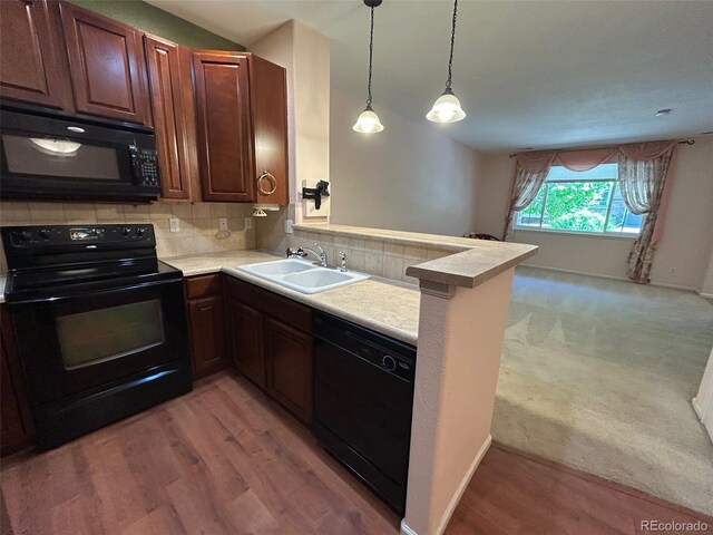 11207 Osage Cir Unit B, Northglenn, CO 80234 - kitchen with black appliances, a sink, a peninsula, light countertops, and backsplash