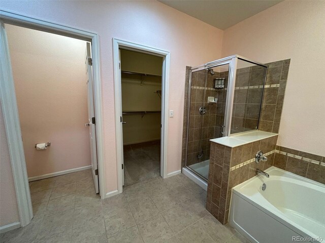 11207 Osage Cir Unit B, Northglenn, CO 80234 - bathroom with a shower stall, a garden tub, a walk in closet, tile patterned flooring, and baseboards