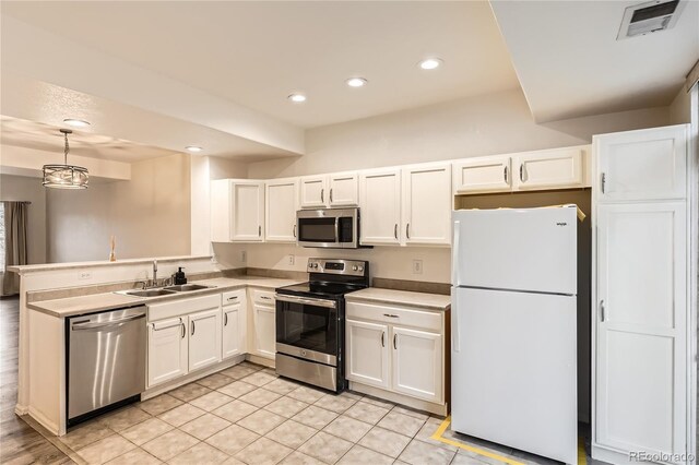 kitchen featuring white cabinetry, appliances with stainless steel finishes, sink, and decorative light fixtures