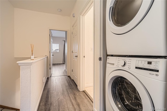 laundry room featuring stacked washer and dryer and light hardwood / wood-style flooring