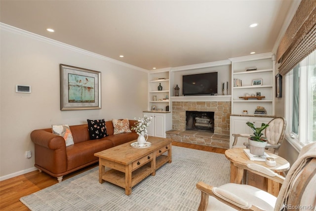 living room with ornamental molding, a stone fireplace, and light hardwood / wood-style floors