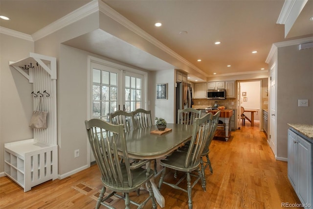 dining area with ornamental molding and light hardwood / wood-style floors