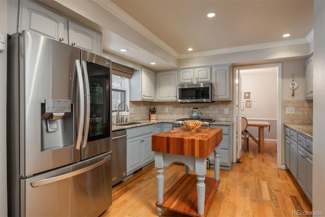 kitchen with crown molding, appliances with stainless steel finishes, a sink, and gray cabinetry