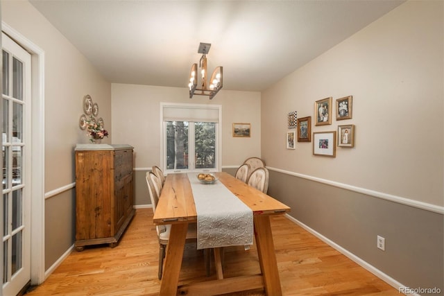 dining area featuring an inviting chandelier, light wood-style flooring, and baseboards