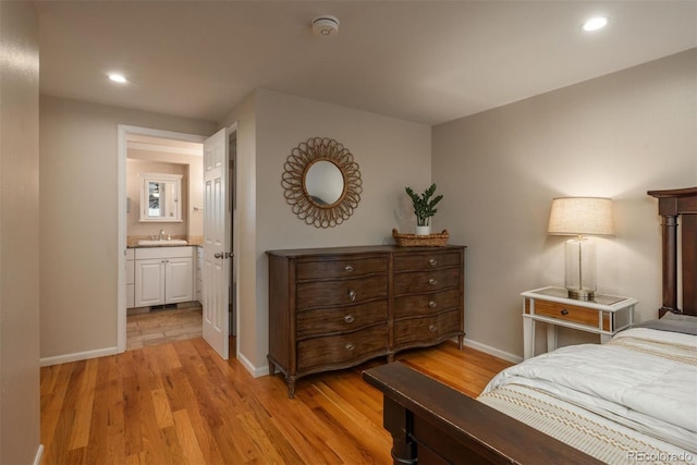 bedroom featuring connected bathroom, recessed lighting, a sink, baseboards, and light wood-style floors