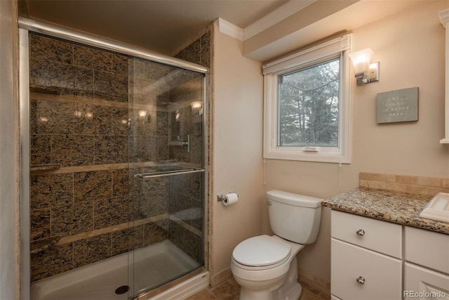 bathroom with baseboards, toilet, crown molding, vanity, and a shower stall