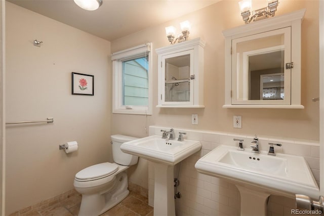 bathroom with toilet and tile walls