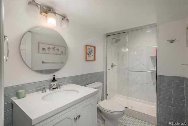 bathroom featuring tile walls, vanity, a shower with shower door, and toilet