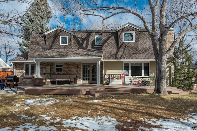 snow covered rear of property with a wooden deck and outdoor lounge area