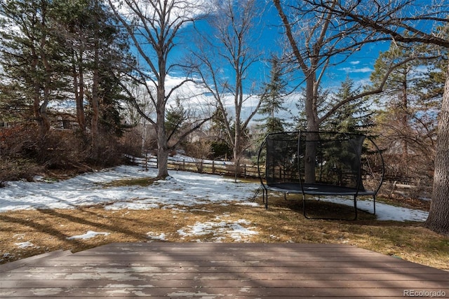 snowy yard with a wooden deck and a trampoline