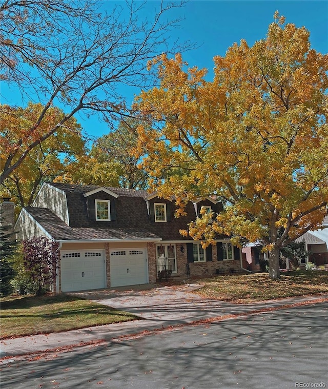 view of front of home featuring an attached garage, a shingled roof, concrete driveway, and brick siding