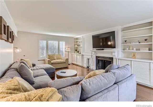 living room with a fireplace, wood-type flooring, and built in shelves