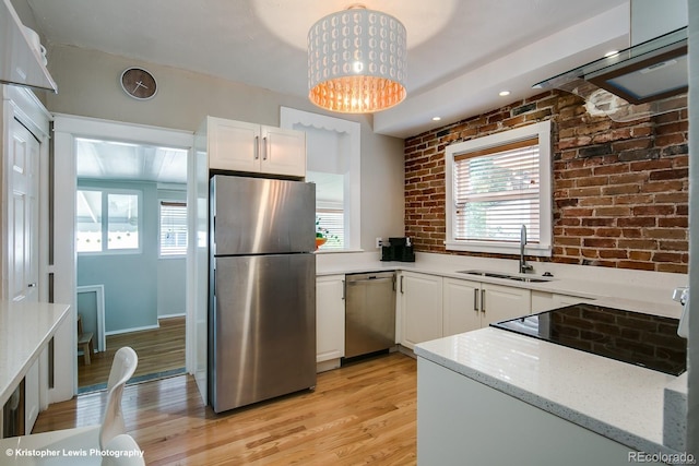 284 S Lafayette St, Denver, CO 80209 - kitchen with appliances with stainless steel finishes, a sink, white cabinets, brick wall, and light wood-style flooring