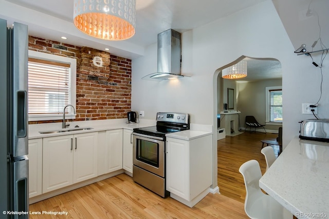 284 S Lafayette St, Denver, CO 80209 - kitchen featuring appliances with stainless steel finishes, wall chimney range hood, a sink, arched walkways, and light wood finished floors