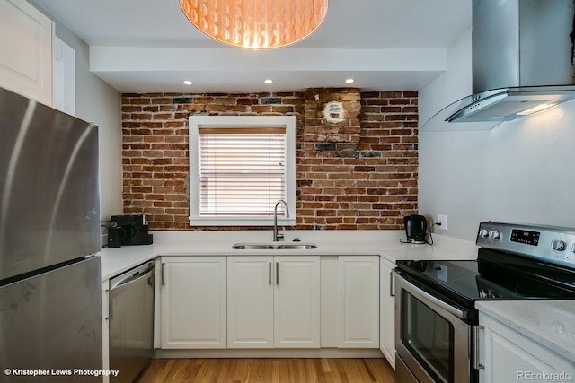 284 S Lafayette St, Denver, CO 80209 - kitchen with appliances with stainless steel finishes, island exhaust hood, a sink, brick wall, and white cabinetry