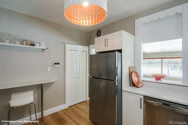 284 S Lafayette St, Denver, CO 80209 - kitchen with appliances with stainless steel finishes, light wood-style floors, light countertops, white cabinetry, and baseboards