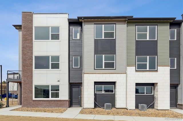 townhome / multi-family property with central AC unit and brick siding