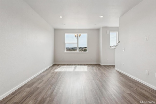 unfurnished room with baseboards, a notable chandelier, recessed lighting, and wood finished floors