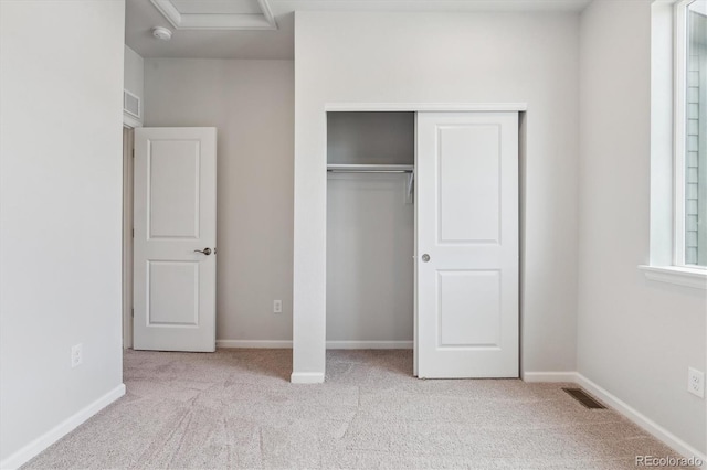 unfurnished bedroom with a closet, attic access, visible vents, and carpet floors