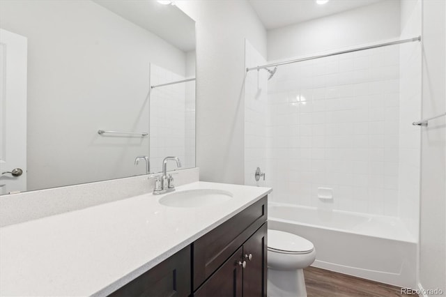 bathroom with toilet, wood finished floors, vanity, and shower / washtub combination