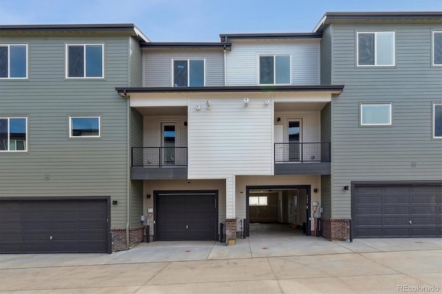 multi unit property with an attached garage, brick siding, and driveway