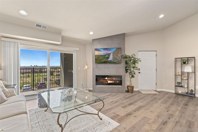 living room featuring a tile fireplace, light hardwood / wood-style flooring, and lofted ceiling