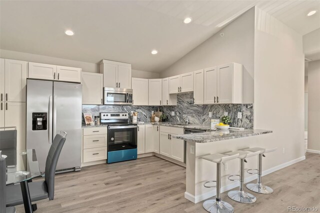 kitchen featuring kitchen peninsula, white cabinetry, light hardwood / wood-style flooring, and appliances with stainless steel finishes