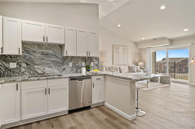 kitchen featuring dishwasher, lofted ceiling, backsplash, sink, and white cabinetry